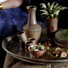 a woman sitting on a chair with plates and vases