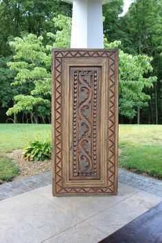 an intricately carved wooden frame sits on the ground in front of some trees and grass