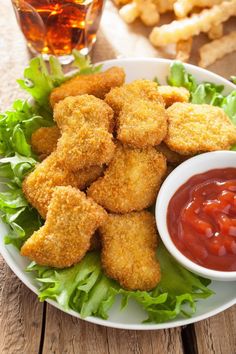 a white plate topped with fried food next to a bowl of ketchup and lettuce