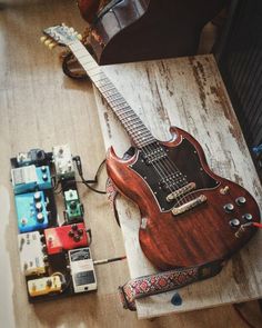 an electric guitar sitting on top of a wooden table next to some other musical equipment