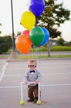 a young boy wearing glasses and holding balloons in the air with a crutch