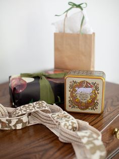 a small box with a ribbon on it sitting on a table next to a brown bag