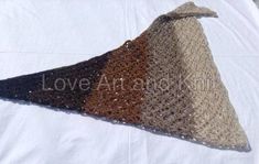 a crocheted triangle is sitting on top of a white sheet with the word love among it