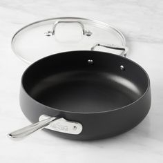 an empty frying pan sitting on top of a white counter next to a pair of tongs