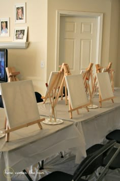 several easels are lined up on a table in front of a television and pictures