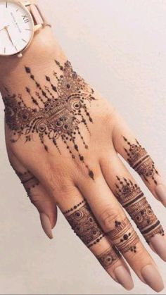 a woman's hand with henna tattoos and a watch on her left wrist