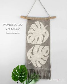 the monster wall hanging is made with yarn and bamboo rafters, along with a green plant