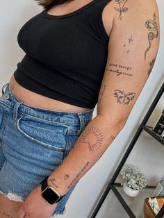 a woman with tattoos on her arm standing next to a shelf