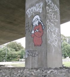 graffiti on the side of a concrete pillar under a bridge