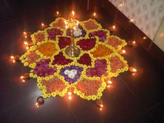 a decorative flower arrangement on the floor with candles around it for diwaling and decorating