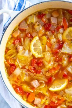 a pot full of soup with lemons, tomatoes and onions