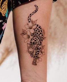 a black and white tattoo on the leg of a woman's legs, with a leopard