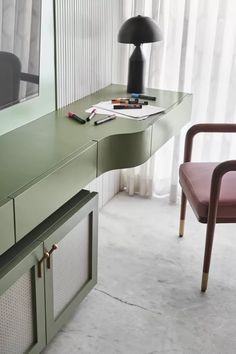 a desk with a lamp and some pens on it next to a chair in front of a window