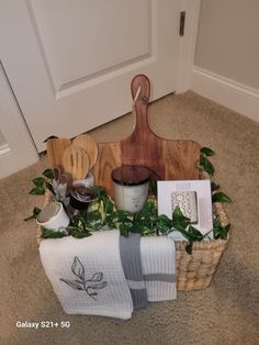 a wooden cutting board sitting on top of a floor next to towels and other items