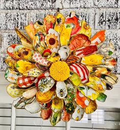 an arrangement of colorful glass flowers in front of a brick wall