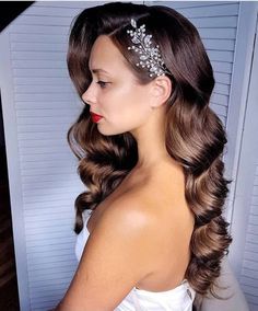 a woman wearing a bridal hair comb with flowers on it's head and long wavy brown hair