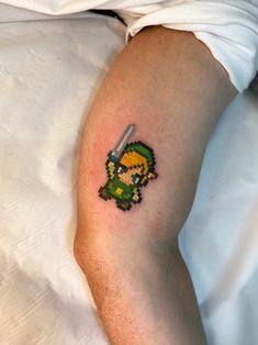 a person laying in bed with a tattoo on their arm that has an image of the legend of zelda