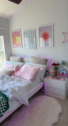 a white bed with pink pillows and blankets