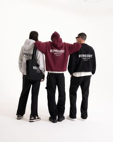 three young men standing in front of a white background wearing hoodies and sweatshirts