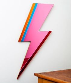 a pink and blue lightning bolt is mounted on the wall next to a wooden table