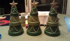 three green christmas trees sitting on top of a table next to each other with gold stars