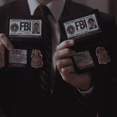 two men in suits holding up their badges