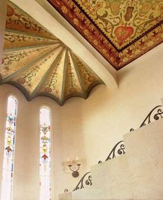 an ornate ceiling in a church with two stained glass windows and decorative designs on the walls