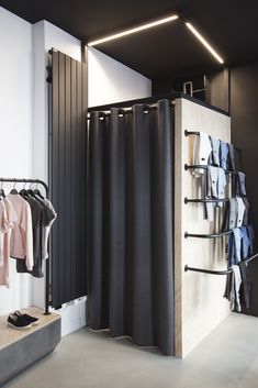 an open closet with clothes hanging on the wall and a rack full of shirts next to it