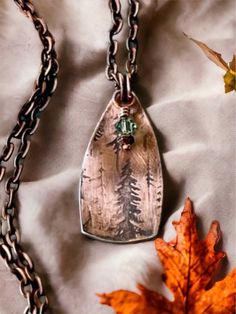 This lovely copper necklace was made from a copper sheet and pressed in a pancake die to cut our tour the shield shap. I rolled the copper sheet in a rolling mill with a pretty tree pattern. I put a black patina on to bring out the pattern in the impression. I added a pretty green crystal that hang down with a copper head pin. I attached copper jump rings and hung it from a 24 inch copper necklace. The pendant is 5/8 inches wide and 1 1/5 inches in length.  This necklace would be a perfect gift Artisan Copper Necklaces With Engraved Details, Artisan Engraved Copper Necklaces, Copper Stamped Necklace Perfect For Gifts, Copper Stamped Necklace For Gift, Brown Stamped Copper Jewelry, Bohemian Engraved Copper Necklaces, Unique Engraved Copper Necklace, Rustic Bronze Soldered Necklace, Rustic Bronze Electroformed Necklace