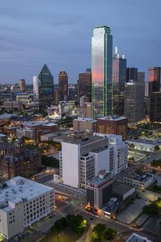 an aerial view of a city at night with skyscrapers and buildings in the foreground