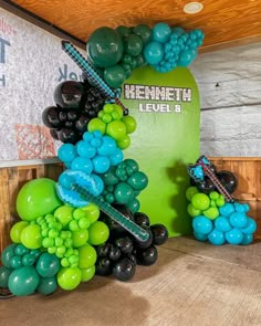 balloons are arranged in the shape of a arch with an arrow on one side and black, green, and blue balloons on the other