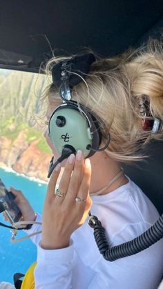 a woman sitting in the cockpit of an airplane with headphones attached to her ears