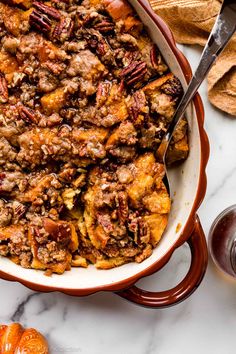 a casserole dish filled with stuffing and topped with pecans next to some crackers