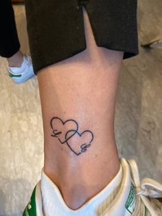 a woman's lower leg with two hearts tattoo on her left side ribcage