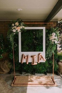 a photo frame with the word mom spelled out on it in front of flowers and greenery