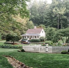 a white picket fence in front of a house with a car parked on the driveway