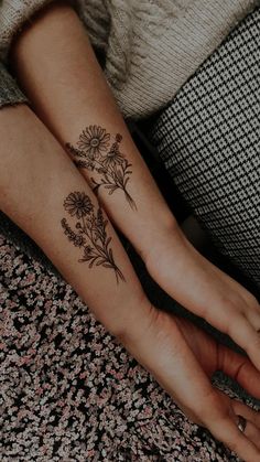 two people holding hands with tattoos on their arms and one has a flower tattoo on the wrist