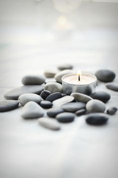 a lit candle surrounded by pebbles and stones