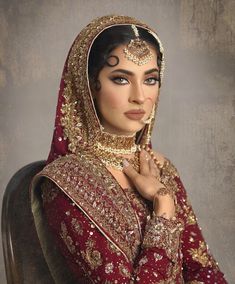 a woman in a red and gold bridal outfit with her hands on her chest