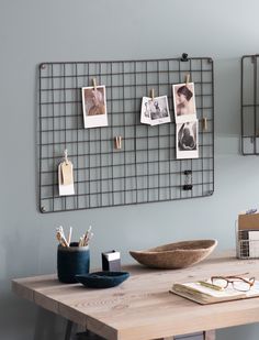 a wooden table topped with a bowl next to a metal grid wall mounted memo board