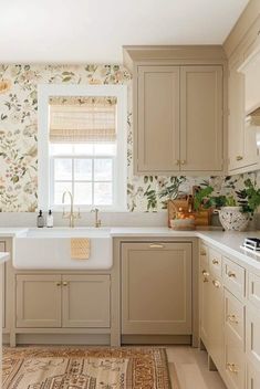 a kitchen with beige cabinets and floral wallpaper on the walls, along with an area rug