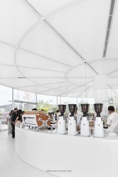 the interior of a restaurant with white walls and ceilings, along with people standing around