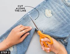 someone is cutting through the holes in their jean pants with a pair of orange scissors