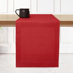 a red table runner with a black mug on it