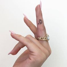 a woman's hand with a ring on top of it and a small tattoo on the middle finger