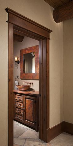 an open door leading to a bathroom with a sink and mirror on the counter top