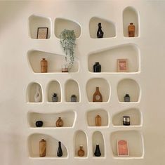 several shelves with vases and other items on them in a white walled wall area