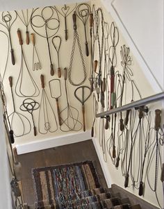 a bunch of necklaces are hanging on the wall next to a stair case in a home