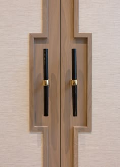 two wooden doors with black handles on each side and one door handle has gold trim