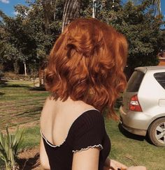 a woman with red hair sitting in the grass